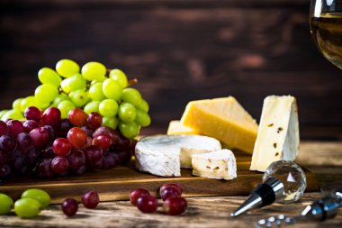 Ahşap arka planda üzüm ve şarap ile iştah açıcı peynir