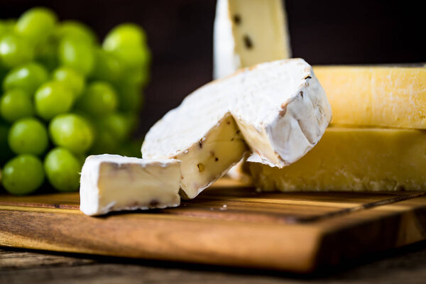 Appetizing cheese with grapes on wooden background