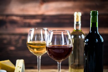 Arka planda şişe ve peynir ile beyaz ve kırmızı şarap Bardakları