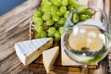 Ahşap arka planda üzüm ve şarap ile iştah açıcı peynir