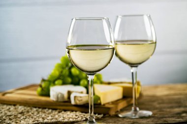 Ahşap arka planda üzüm ve şarap ile iştah açıcı peynir