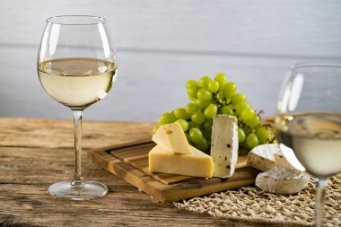 Ahşap arka planda üzüm ve şarap ile iştah açıcı peynir
