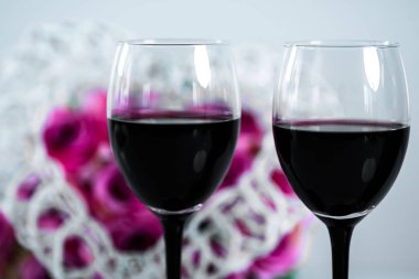 Açık arka planda gözlük ve çiçek kırmızı şarap