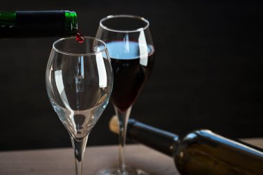 Siyah arka planda iki şişe ve şarap gözlüğü