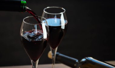 Siyah arka planda iki şişe ve şarap gözlüğü