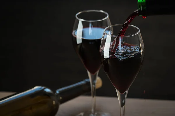 Two bottles and wine glasses on black background