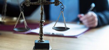 Yargıç, hukuk ve adalet sembolleriyle masada çalışıyor.