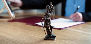 Yargıç, hukuk ve adalet sembolleriyle masada çalışıyor.