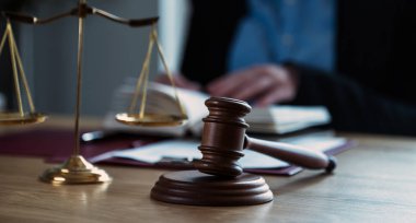 Önplanda hukukun ve adaletin sembolleriyle masada çalışan yargıç