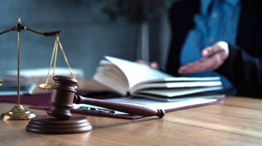 Önplanda hukukun ve adaletin sembolleriyle masada çalışan yargıç