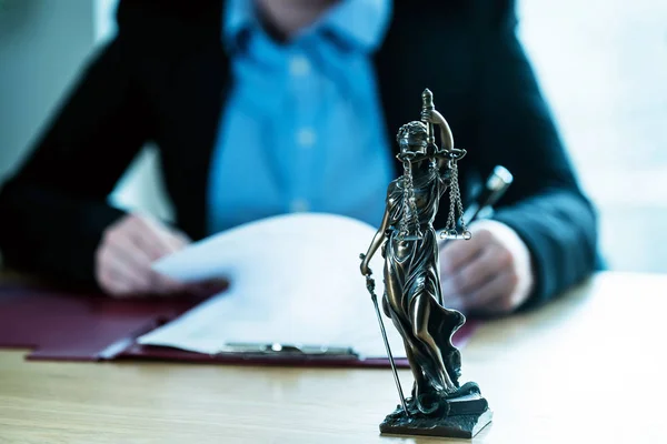 Judge working at table with symbols of law and justice