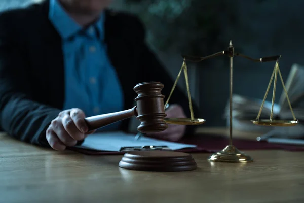 Judge working at table with symbols of law and justice on foreground