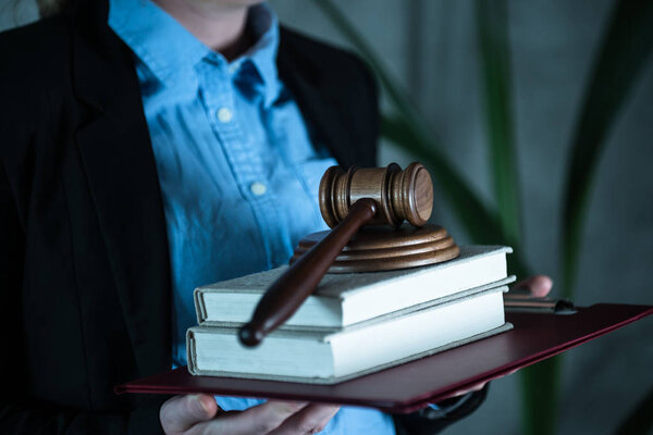 Judge holding books with gavel in hands