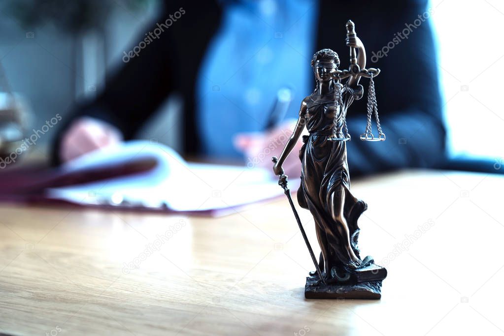 Judge working at table with symbols of law and justice