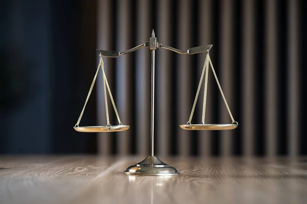 Law and Justice, scales on wooden table with blurred background.