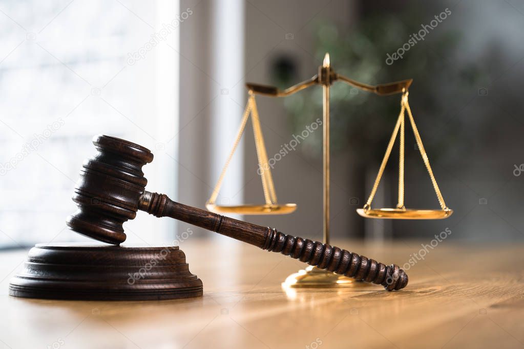 Law and Justice, judge gavel and scales on wooden table with blurred background.