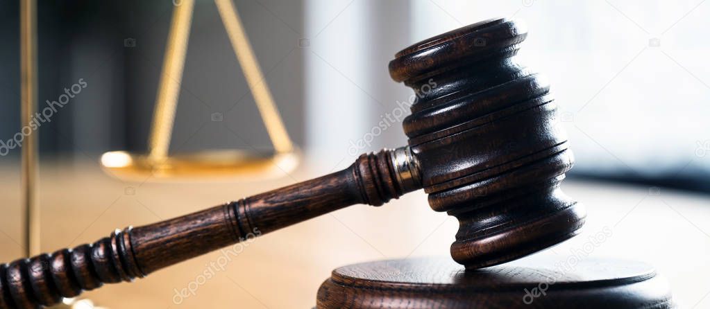 Law and Justice, judge gavel and scales on wooden table with blurred background.