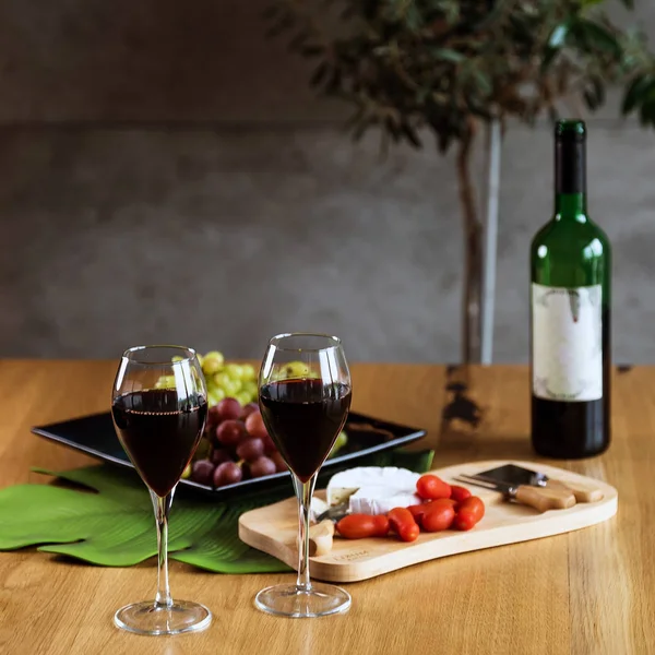red wine with grapes and bottle on wooden table