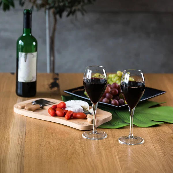Üzümlü kırmızı şarap ve tahta masada şişe.
