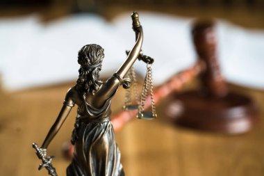 Hukuk ve Adalet, kör tanrıça Themis 'in heykeli ahşap masanın üzerinde bulanık arka planda..