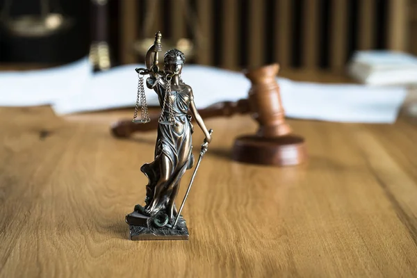 Law and Justice, Statue of blind goddess Themis on wooden table with blurred background.