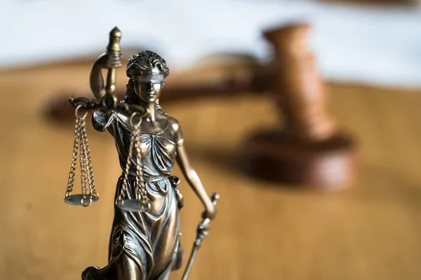 Law and Justice, Statue of blind goddess Themis on wooden table with blurred background.