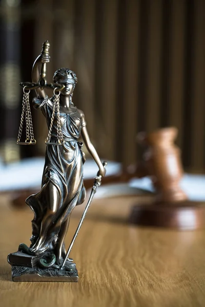 Law and Justice, Statue of blind goddess Themis on wooden table with blurred background.