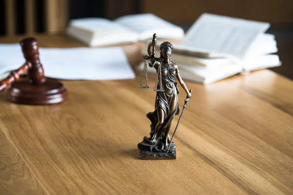 Law and Justice, Statue of blind goddess Themis on wooden table with blurred background.