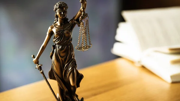 Law and Justice, Statue of blind goddess Themis on wooden table with blurred background.