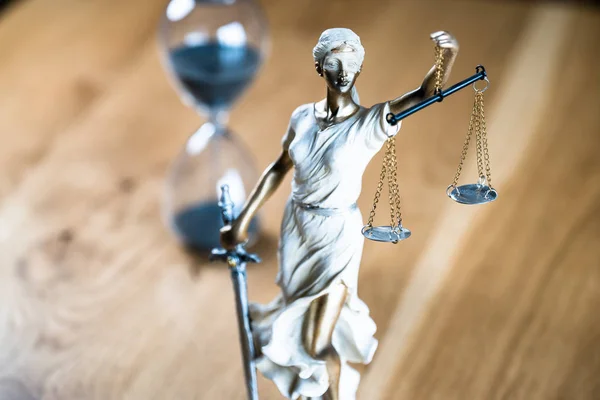 Law and Justice, Statue of blind goddess Themis on wooden table with blurred background.