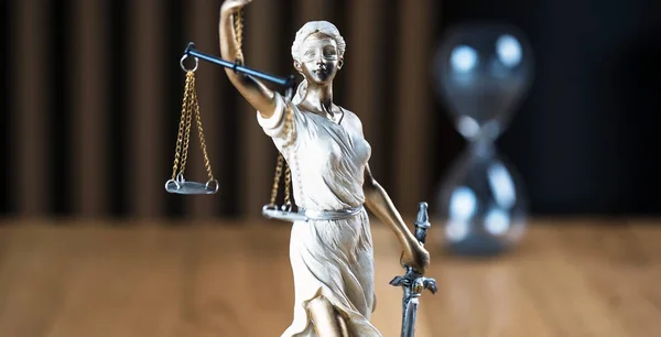 Law and Justice, Statue of blind goddess Themis on wooden table with blurred background.