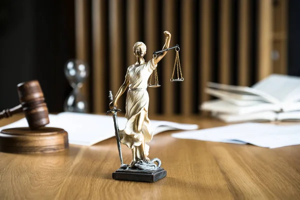 Law and Justice, Statue of blind goddess Themis on wooden table with blurred background.