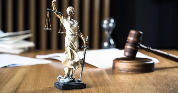 Law and Justice, Statue of blind goddess Themis on wooden table with blurred background.