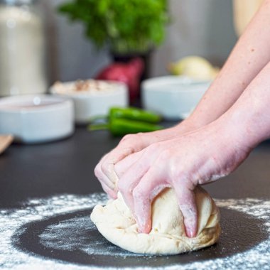 Genç bir kadın mutfakta hamur pişiriyor.