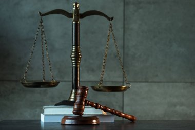 Hukuk ve Adalet sembolleri ahşap masa üzerinde bulanık kitap arkaplanı.