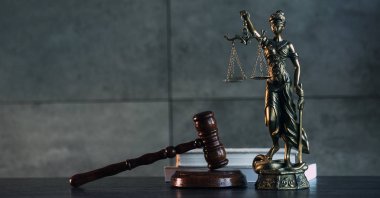 Hukuk ve Adalet sembolleri ahşap masa üzerinde bulanık kitap arkaplanı.