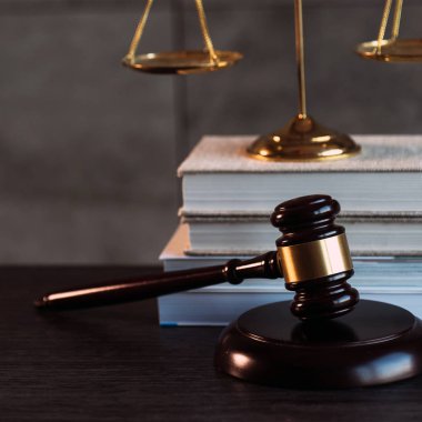 Hukuk ve Adalet sembolleri ahşap masa üzerinde bulanık kitap arkaplanı.