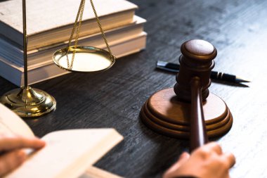 Yargıç, hukuk ve adalet sembolleriyle masada çalışıyor.