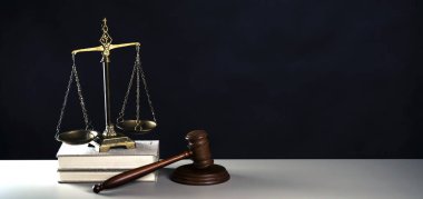 Hukuk ve Adalet sembolleri ahşap masa üzerinde bulanık kitap arkaplanı.