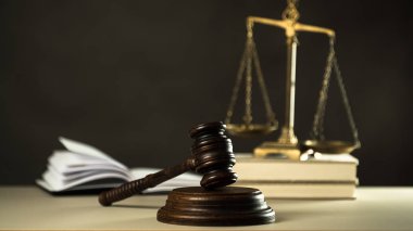 Hukuk ve Adalet sembolleri ahşap masa üzerinde bulanık kitap arkaplanı.