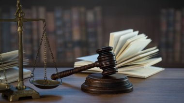 Hukuk ve Adalet sembolleri ahşap masa üzerinde bulanık kitap arkaplanı.