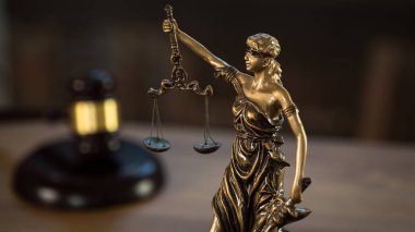 Hukuk ve Adalet sembolleri ahşap masa üzerinde bulanık kitap arkaplanı.