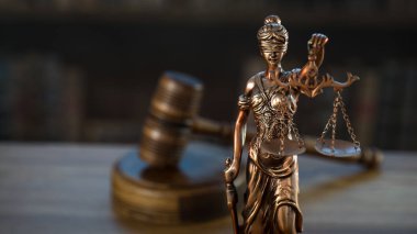 Hukuk ve Adalet sembolleri ahşap masa üzerinde bulanık kitap arkaplanı.