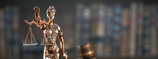Law and Justice symbols on wooden table with blurred books background.