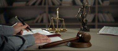 Yargıç, hukuk ve adalet sembolleriyle masada çalışıyor.