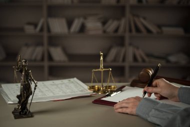 Yargıç, hukuk ve adalet sembolleriyle masada çalışıyor.