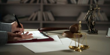 Yargıç, hukuk ve adalet sembolleriyle masada çalışıyor.