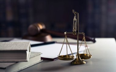 Ahşap masa arkasında hukuk ve adalet sembolleri..