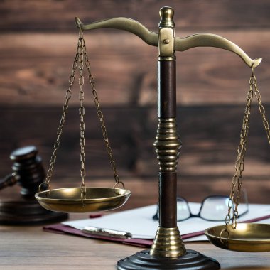 Ahşap masa arkasında hukuk ve adalet sembolleri..