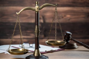 Ahşap masa arkasında hukuk ve adalet sembolleri..